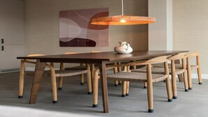 Un comedor moderno con una mesa y sillas de madera, un lámpara colgante y un jarrón decorativo sobre la mesa.
