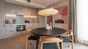 A modern kitchen with grey cabinets, a round dining table with chairs, and a pendant light.
