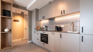 A modern kitchen with white cabinets, a built-in oven, and a coffee maker.