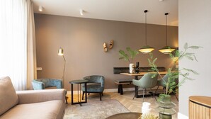 A modern living room with a sofa, chairs, a coffee table, and a dining area with chairs and a table. - 3-bedroom duplex apartment in Den Haag (Den Haag)