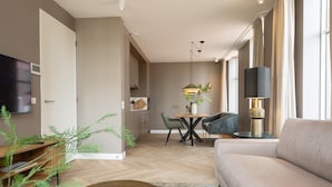 Een moderne woonkamer met een bank, een eettafel met stoelen, een televisie en een lamp.