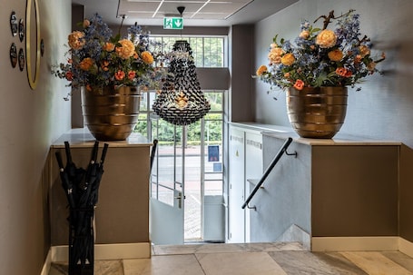 A modern interior with two large metallic flower pots on a counter, a hanging light fixture, and a glass door leading outside.