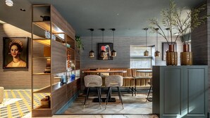 A modern interior with a wooden bookshelf, two bar stools, a dining table, and hanging pendant lights. - Modern Stay in Historic Delft (Den Haag)