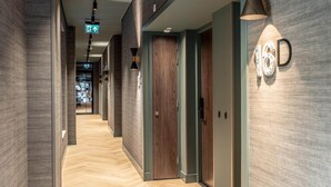 A modern hallway with a herringbone floor, wooden doors, and a wall-mounted sign indicating room number 16D. - Modern Stay in Historic Delft (Den Haag)