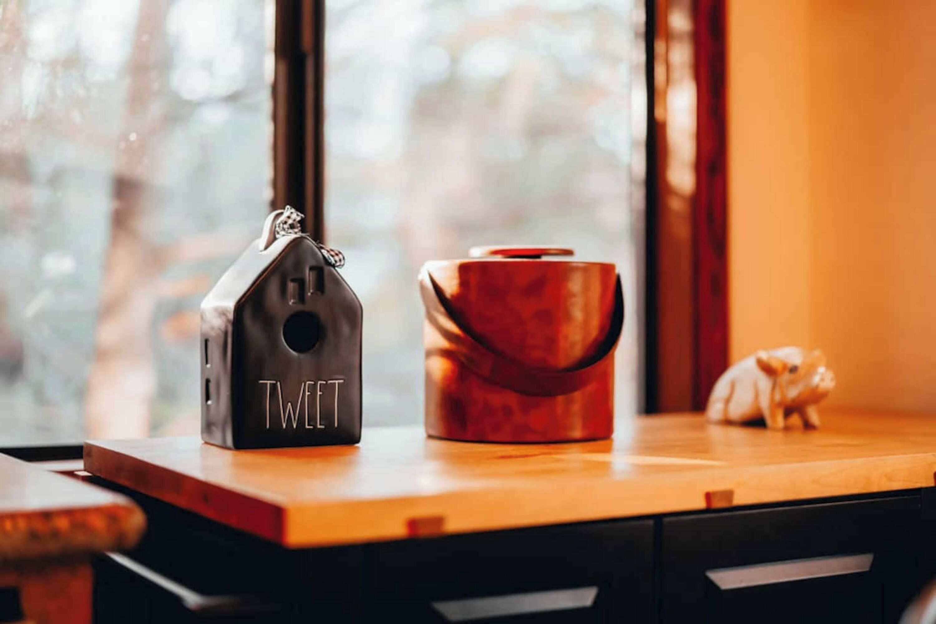 A wooden table with a black object labeled "TWEET" and a red container.