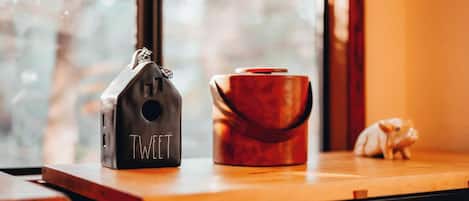 A wooden table with a black object labeled "TWEET" and a red container.