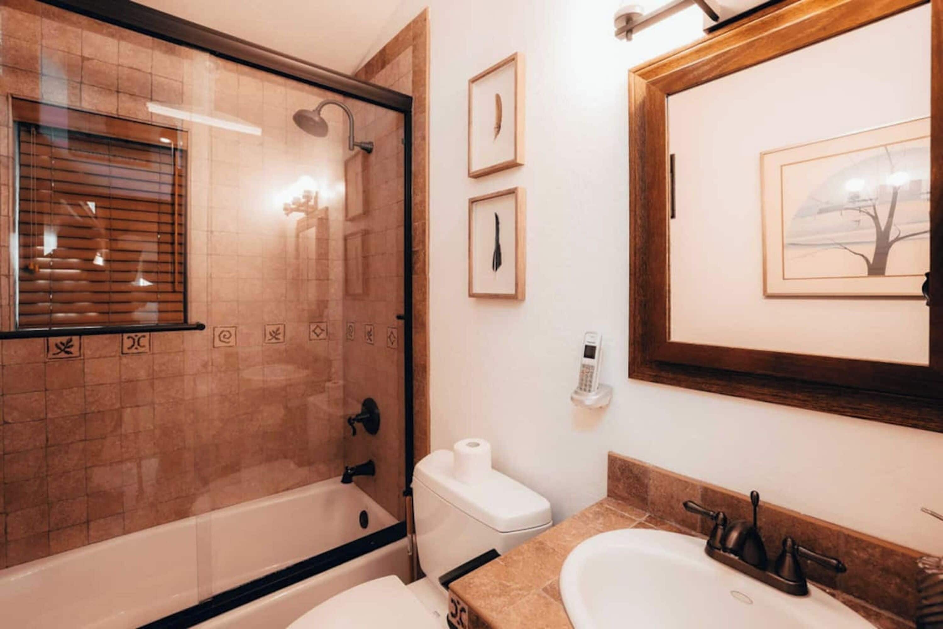 Une salle de bain dotée d’une douche à parois de verre, de toilettes, d’un lavabo et d’œuvres d’art encadrées accrochées au mur.