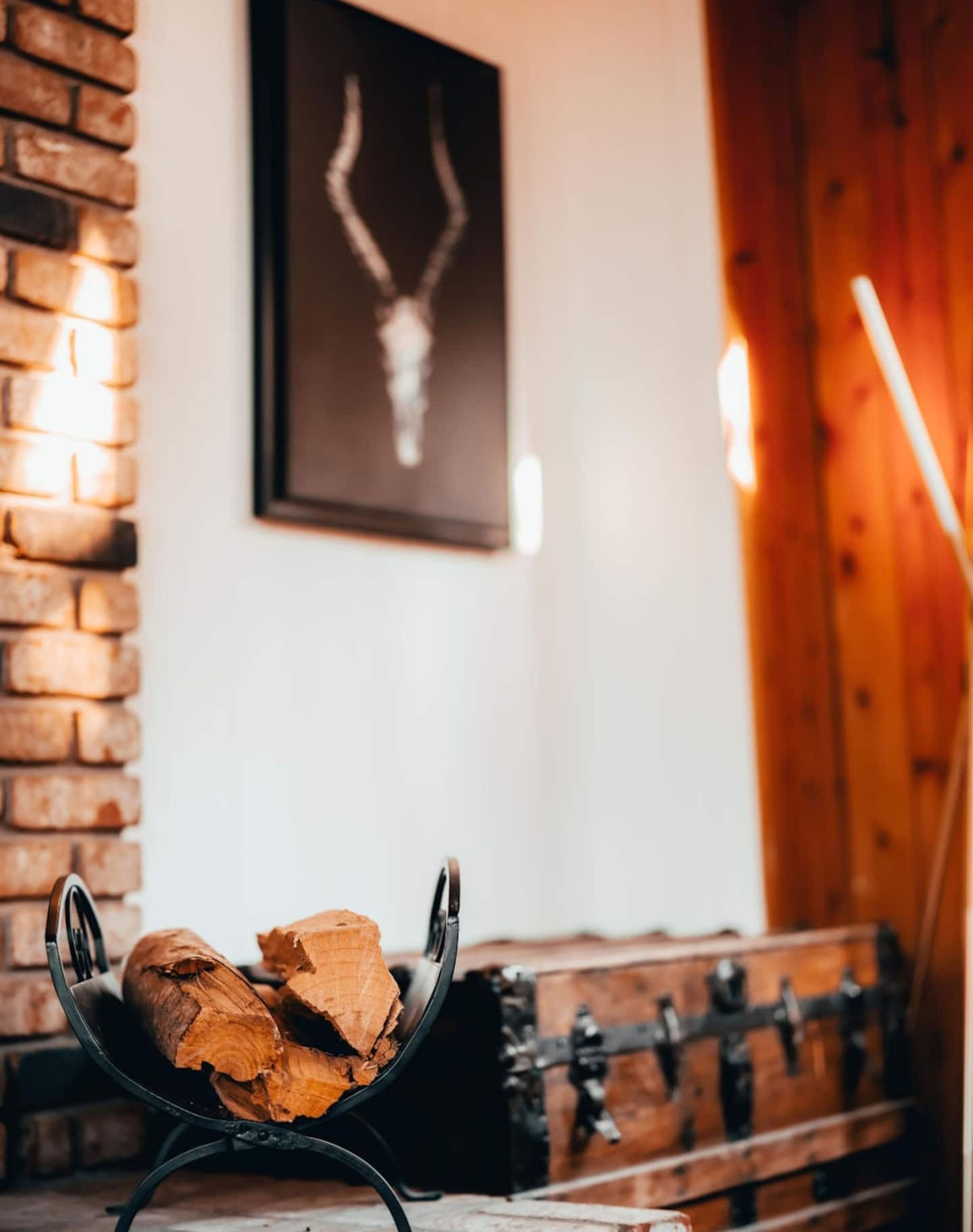 Una chimenea con un soporte de metal que sostiene leña, una pared de ladrillo y una pared de paneles de madera con un cuadro colgado.
