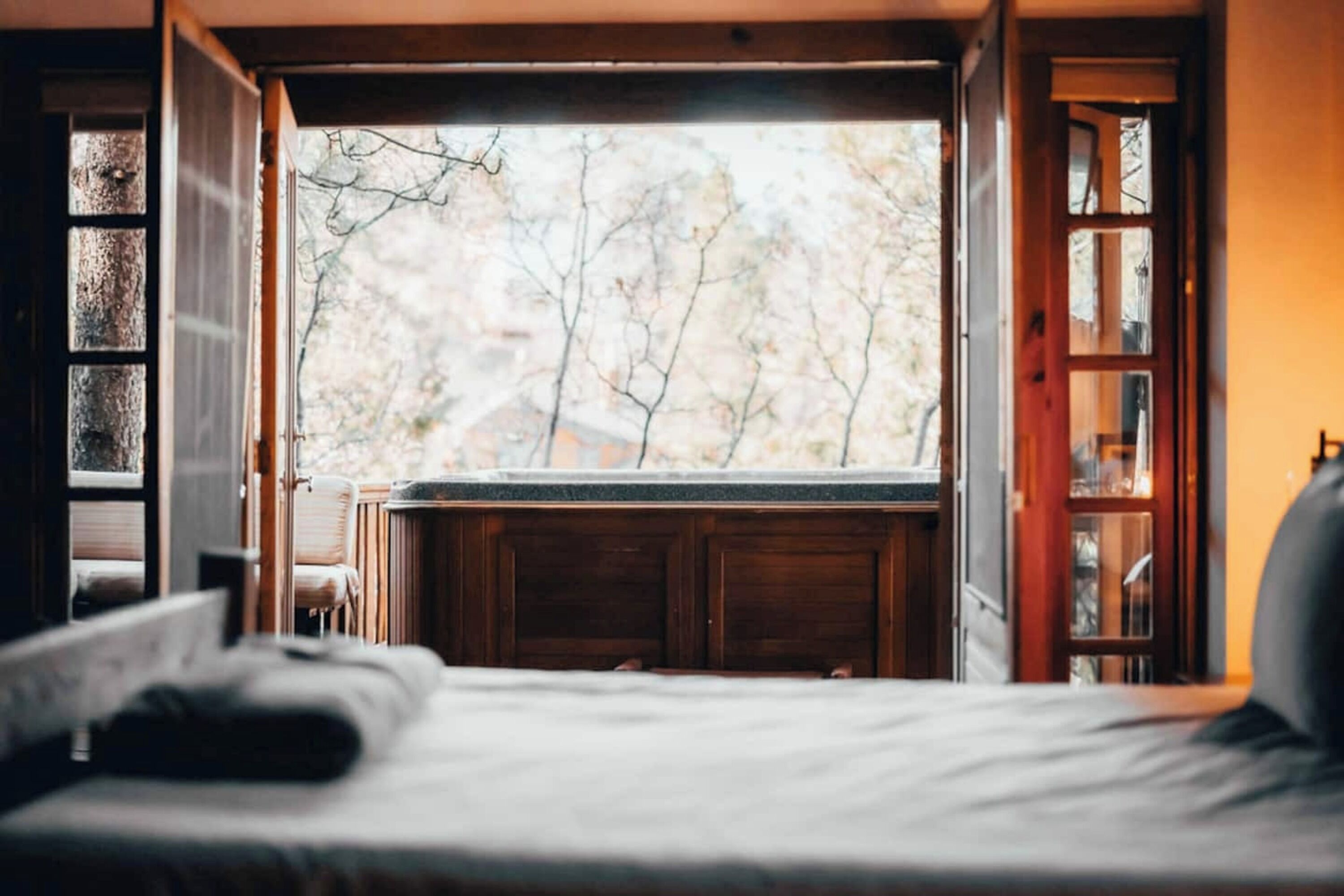 Ein Schlafzimmer mit großem Fenster, einem Bett und einem Holzkasten.