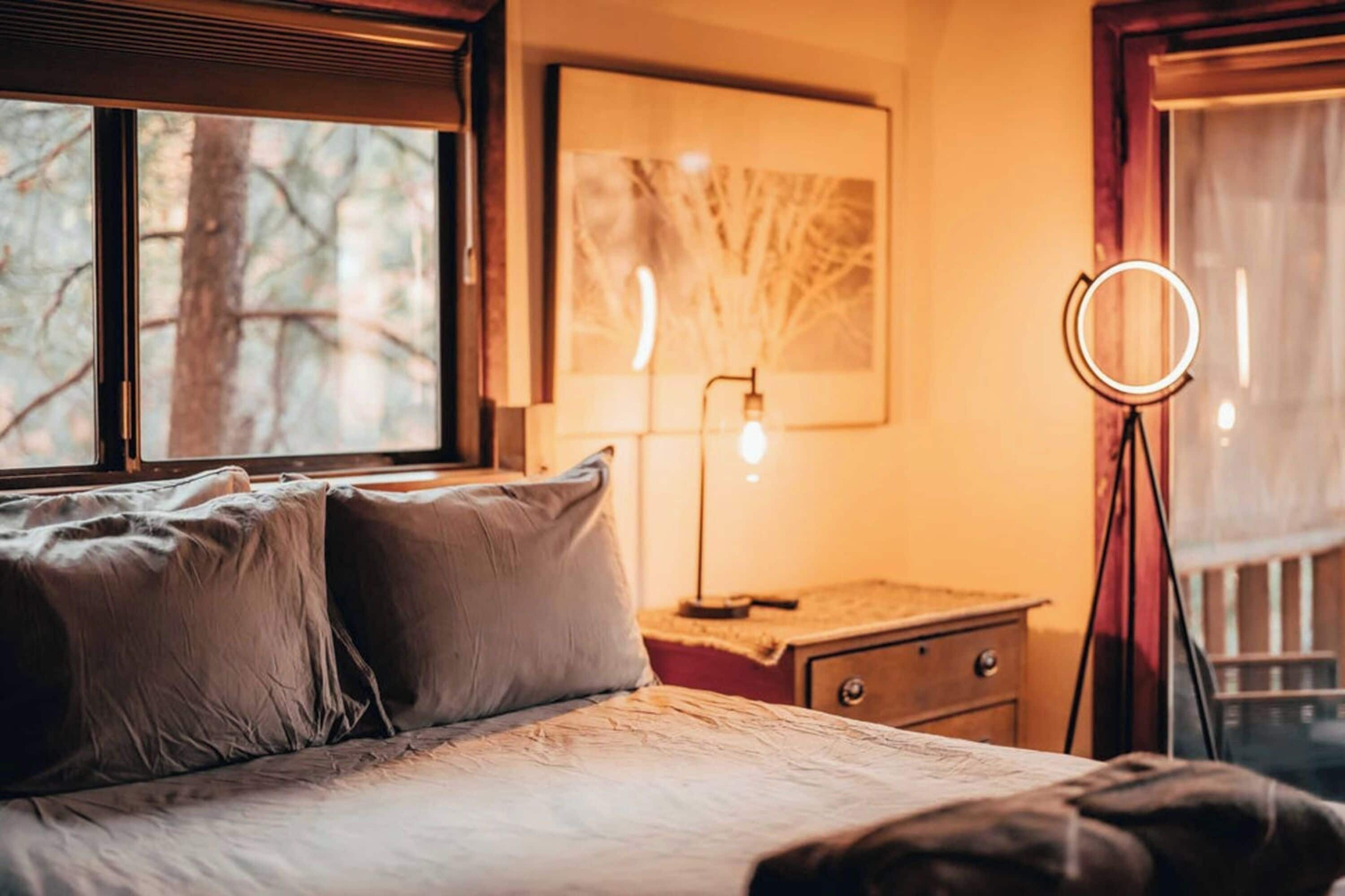 Un dormitorio con una cama, una mesita de noche, una lámpara y un aro iluminador.