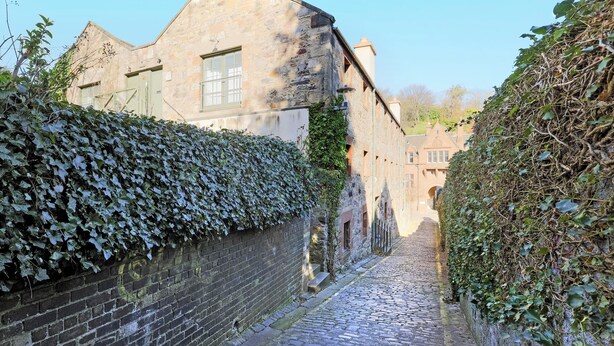 A narrow cobblestone street flanked by stone buildings with ivy-covered walls. - Secluded Brewery Apartment   (Edinburgh)