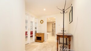 A hallway with a wooden table, a coat rack, and a mirror on the wall. - Secluded Brewery Apartment   (Edinburgh)