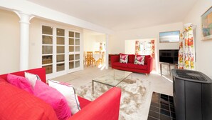 A living room with a red sofa, a glass coffee table, and a black heater. There is a TV and a painting on the wall. - Secluded Brewery Apartment   (Edinburgh)