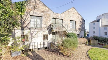 A stone building with a traditional design, featuring a small garden area with gravel paths and potted plants.