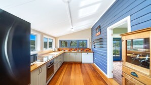 Una cocina moderna con suelo de madera, armarios blancos y pared azul exterior.