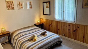 A bedroom with a wooden paneled wall, a large window with curtains, a bed with striped bedding, and three wall-mounted art pieces. - L'Esprit d'Autrefois - authentic guest house (Cublac)