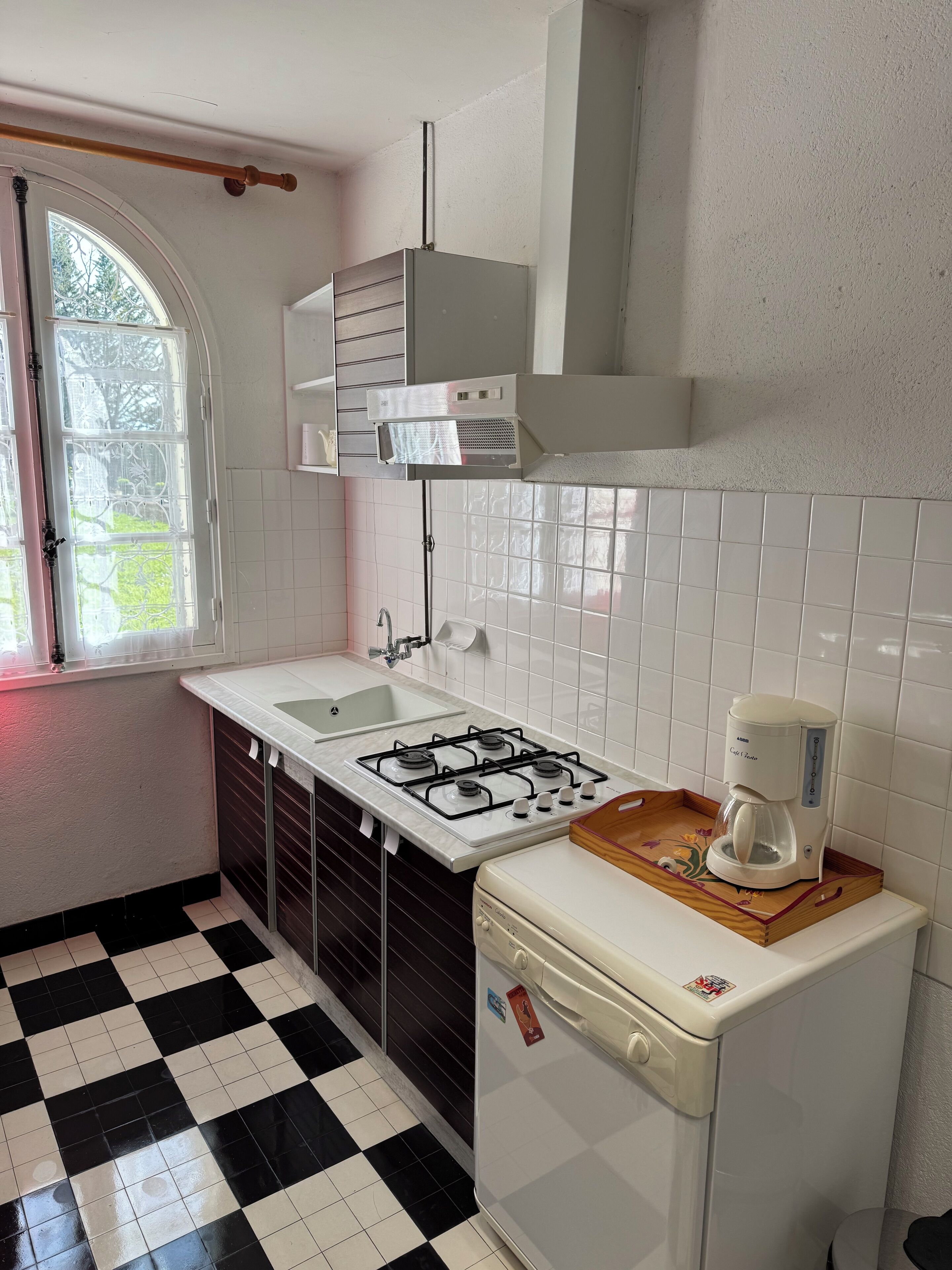A kitchen with a gas stove, a coffee maker, and a refrigerator.