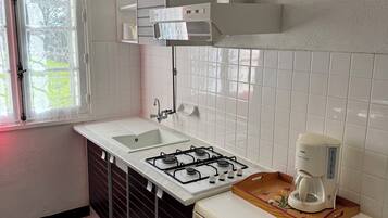 A kitchen with a gas stove, a coffee maker, and a refrigerator.