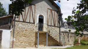 A stone building with a small balcony and a staircase leading to a second floor. - L'Esprit d'Autrefois - authentic guest house (Cublac)