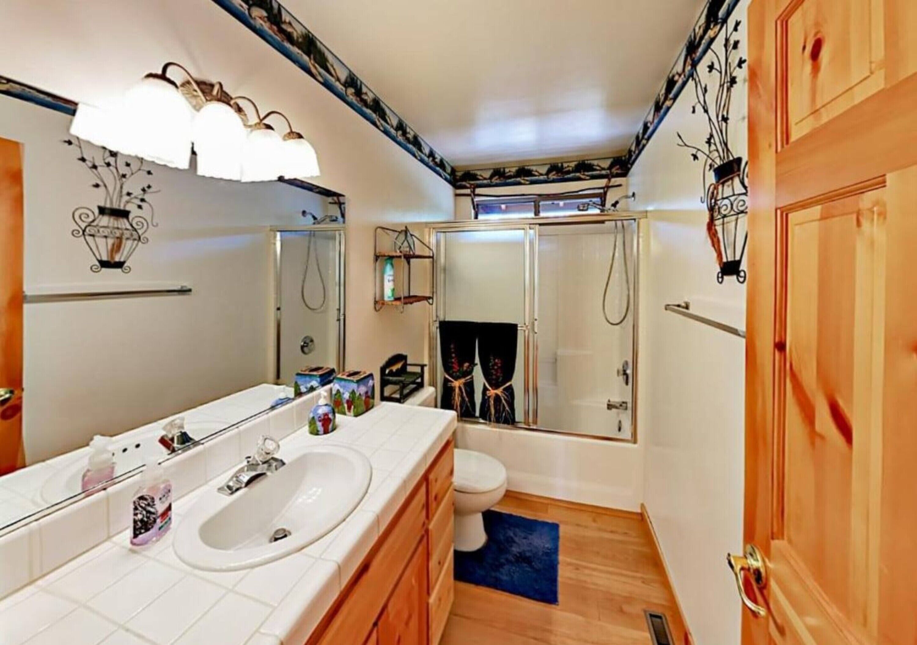 Une salle de bain avec un grand miroir, un lavabo, des toilettes et une douche.