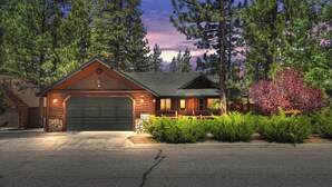 A log cabin with a garage, surrounded by trees and a well-maintained lawn. - Teakwood Cozy Wood Cabin with Fireplace (Big Bear Lake)