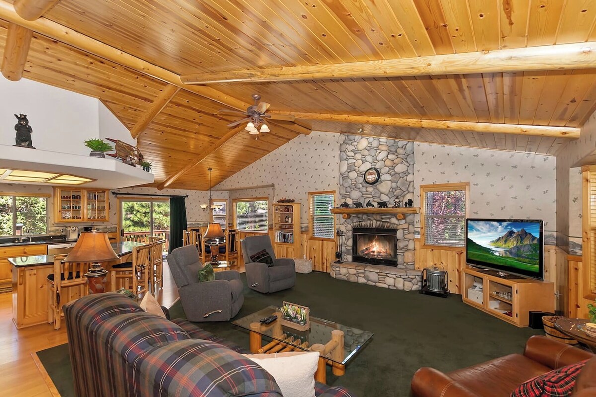 A cozy living room with a fireplace, wooden ceiling, and a television.