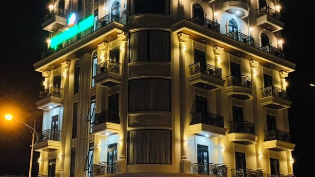 A multi-story hotel with balconies and a prominent green sign. - Blue Ocean Hotel Phan Thiet - BAY LUXURY (Phu Thuy)