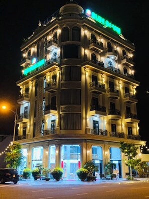 A multi-story hotel with balconies and a prominent green sign. - Blue Ocean Hotel Phan Thiet - BAY LUXURY (Phu Thuy)