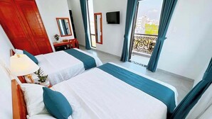A hotel room with two beds, a wooden wardrobe, a desk with a chair, a TV, and large windows with curtains. - Blue Ocean Hotel Phan Thiet - BAY LUXURY (Phu Thuy)