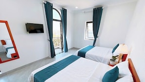 A hotel room with two beds, a TV, a balcony, and a window with curtains. - Blue Ocean Hotel Phan Thiet - BAY LUXURY (Phu Thuy)