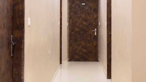 Un couloir avec une porte en bois portant le numéro 304, un plafond au design moderne et un sol carrelé, propre et bien entretenu.