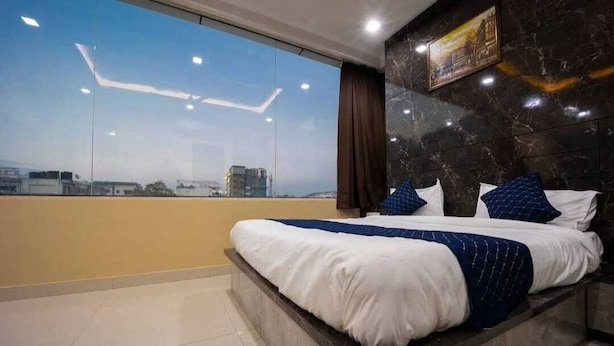 Une chambre d’hôtel moderne avec un grand lit, une vue sur la ville et un mur en marbre.