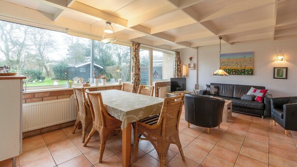 A dining area with a table and chairs, a sofa, and a television.