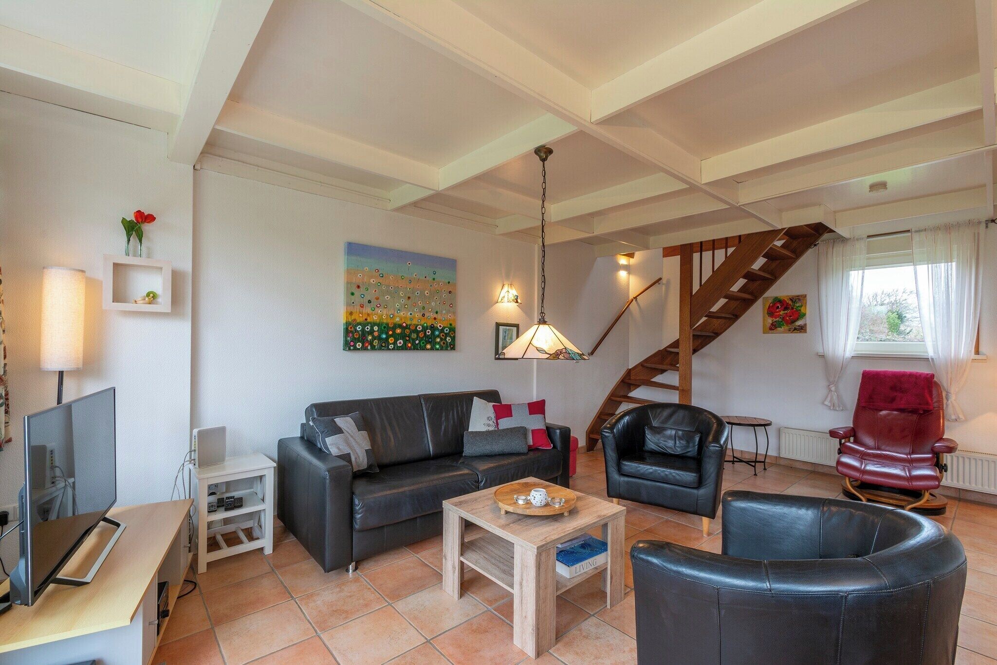 A modern living room with a sofa, a coffee table, a TV, and a staircase.