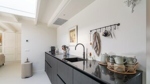 Una cocina moderna con encimera negra, un lavamanos y una estantería colgante para ollas.
