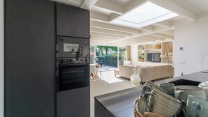 Una cocina moderna con horno empotrado y comedor con mesa y sillas.