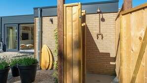 Una puerta de madera que da a una casa moderna con fachada de ladrillo y puerta de cristal.