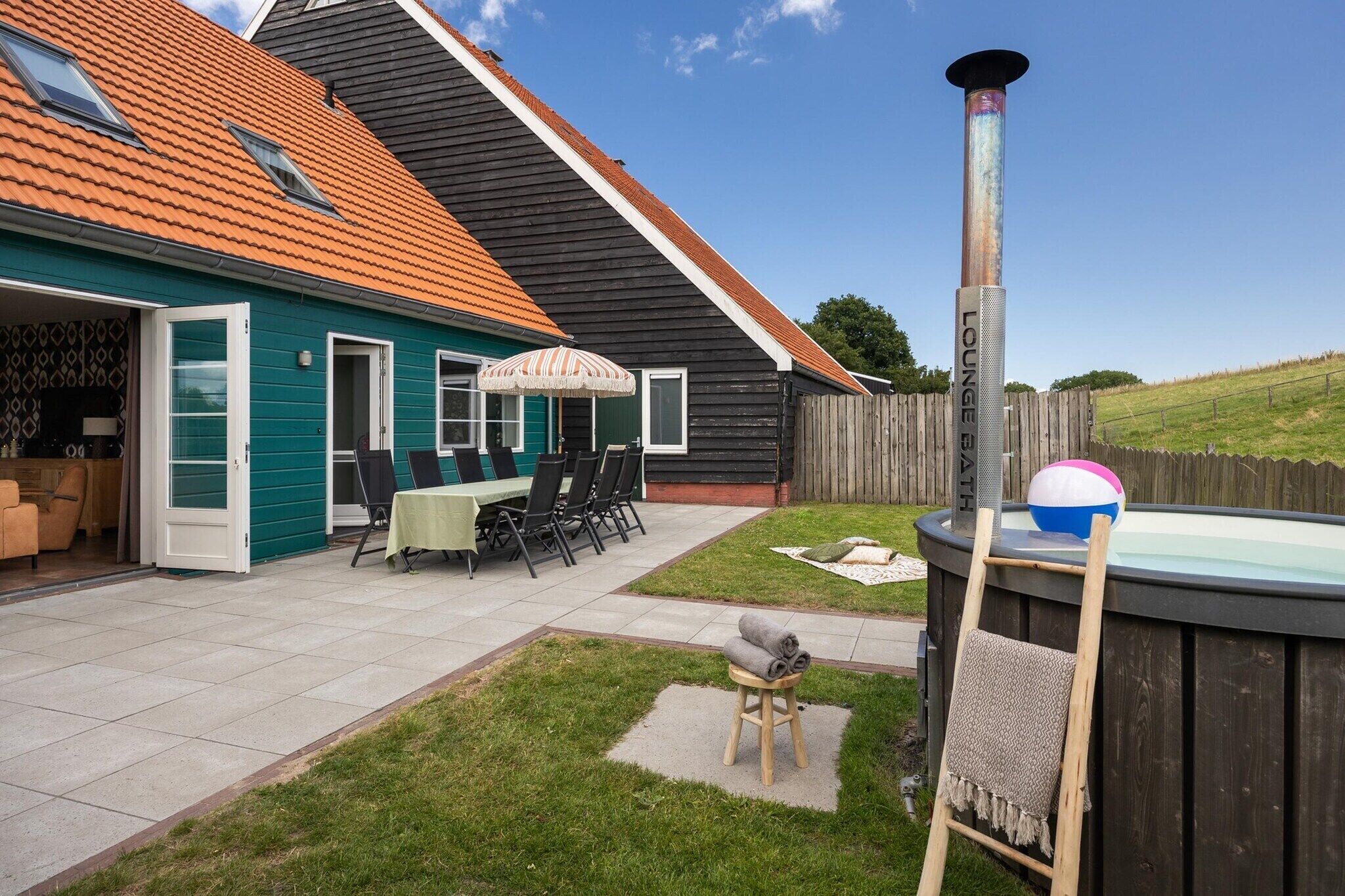 A backyard with a hot tub, a wooden deck, and a covered patio area.