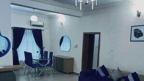 Una sala de estar moderna con un sofá azul, una mesa de centro y un comedor con sillas y una mesa.