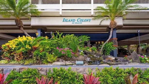Außenansicht des Island Colony Hotels mit angelegtem Garten und einem Schild über dem Eingang.
