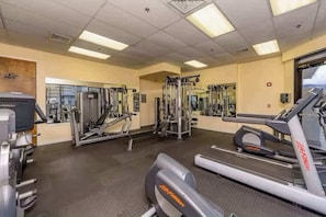 Une salle de sport équipée de divers appareils d’exercice, notamment des tapis de course, des appareils de musculation et des poids libres.