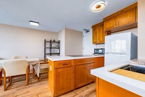 Une cuisine moderne avec des meubles en bois, un plan de travail blanc et un four encastré.