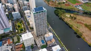 Eine Luftaufnahme einer Stadtlandschaft mit einem Fluss, Hochhäusern und einem Sportplatz.