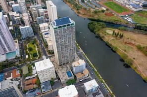 An aerial view of a cityscape with a river, high-rise buildings, and a sports field.