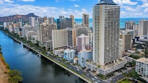 Ein hoch aufragendes Gebäude mit modernem Design, gelegen am Fluss mit einer Brücke.