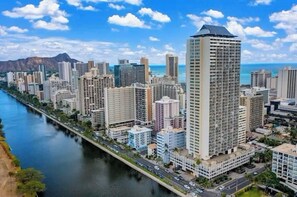 A high-rise building with a modern design, situated next to a river with a bridge.