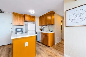 Een kleine keuken met houten kastjes, een centraal eiland en een ingebouwde vaatwasser.