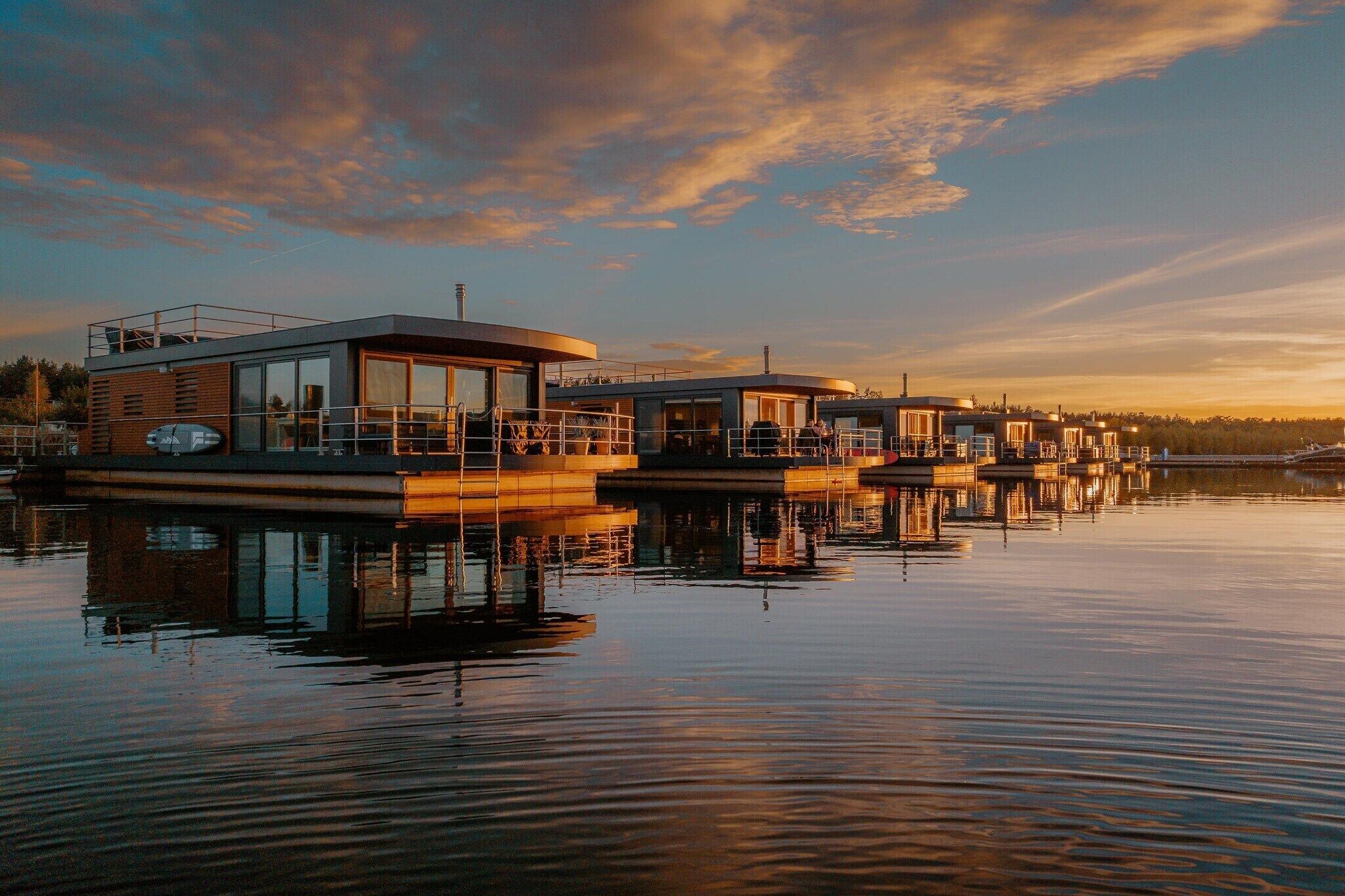 A waterfront property with multiple floating structures, each featuring large windows and a covered outdoor area.