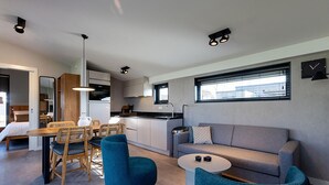 Een moderne woonkamer met een bank, twee stoelen, een salontafel en een eethoek met tafel en stoelen.