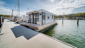 A modern dock with a floating structure featuring a covered area, a flag, and a waterway.